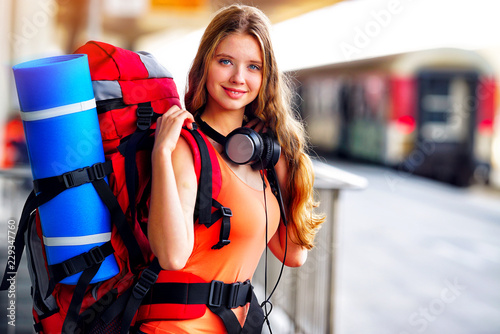 Fotografía Traveller girl female wear headphones with backpack and tourism outfit at railway station city outdoor