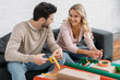 © LIGHTFIELD STUDIOS - smiling couple preparing christmas gift box together, holding ribbons and looking at each other at home