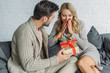 © LIGHTFIELD STUDIOS - handsome young man presenting gift for surprised girlfriend at home