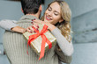 © LIGHTFIELD STUDIOS - beautiful young woman with gift box embracing her boyfriend at home