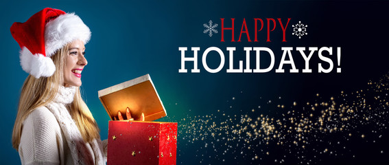 Happy holidays message with young woman with Santa hat opening a gift box