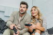 © LIGHTFIELD STUDIOS - smiling young couple playing video games together on couch at home