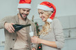 © LIGHTFIELD STUDIOS - happy young couple pouring champagne into glasses in front of christmas tree at home