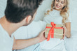 © LIGHTFIELD STUDIOS - cropped shot of young man presenting gift to girlfriend in bed at home
