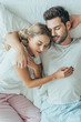 © LIGHTFIELD STUDIOS - top view of happy young couple sleeping together and hugging in bed at home