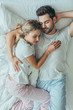 © LIGHTFIELD STUDIOS - top view of beautiful young couple sleeping together and embracing in bed at home