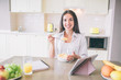 © estradaanton - Happy ans positive girl is smiling on camera. She holds a spoon with milk and corn flakes. She is sitting in kitchen.