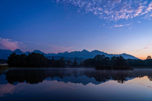 Blue Hour Shot Of Peaceful Scene Of Beautiful Autumn Mountain Landscape With Lake, Colorful Trees And High Peaks In High Tatras, Slovakia.