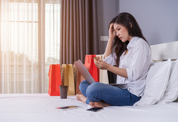 Sticker - stressed woman using laptop for online shopping on bed, and having problem with blocked credit card