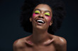 © LIGHTFIELD STUDIOS - happy african american model with bright neon makeup posing isolated on black