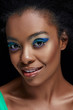 © LIGHTFIELD STUDIOS - portrait of beautiful african american model with bright blue eyes shadows isolated on black