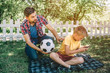 © estradaanton - Good father is looking at his son and holding a ball. He wants to play with his son. Child is playing on phone. He doesn't want to play football.