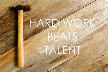inspirational and motivational quotes.hard work beats talent. hammer on wooden background.