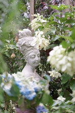 Garden Statue. A Beautiful Stone Statue Of A Woman With A Turban And Flowers On Her Hair In The Mysteriously Secret Garden.