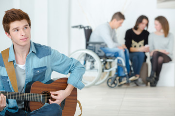 young man playing a guitar in a school