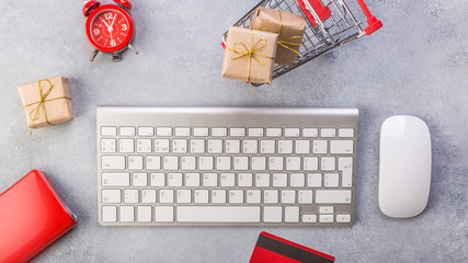 Concept online shopping buying presents. Red credit card, keyborad and christmas presents on grey table flat lay, copy space