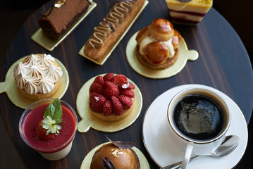 Wall Mural - Breakfast time with cup of hot coffee and pieces of cream cake with strawberries and raspberries, sweets dessert breakfast snacks, close-up. Berry cupcakes dessert on wooden table background, top view