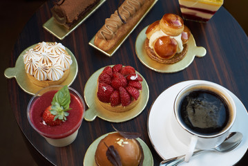 Wall Mural - Breakfast time with cup of hot coffee and pieces of cream cake with strawberries and raspberries, sweets dessert breakfast snacks, close-up. Berry cupcakes dessert on wooden table background, top view