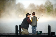 Smiling Grandfather And Grandson Fishing In Lake