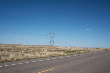 HIGH VOLTAGE POWER TOWERS IN FIELD WITH BLUE SKY, USA