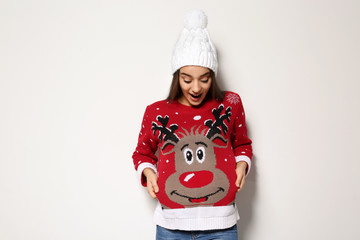 Poster - Young woman in Christmas sweater and knitted hat on white background