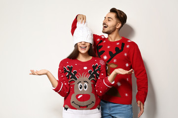 Young couple in Christmas sweaters on white background