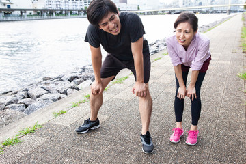 トレーニングの後。息が上がって中腰の夫婦。