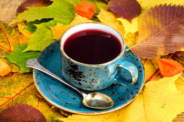 Canvas Print - Сup of hot red tea from karkade, beautiful autumn leaves on table