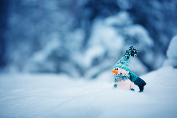 Wall Mural - little knitted snowmans on soft snow on blue background