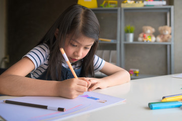 Cute little girl doing homework, reading a book, coloring pages, writing and painting. Children paint. Kids draw. Preschooler with books at home. Preschoolers learn to write and read. Creative toddler