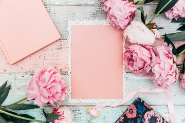 Sticker - pink peony flowers with greeting card on wooden background. Minimal flat lay composition with copy space.