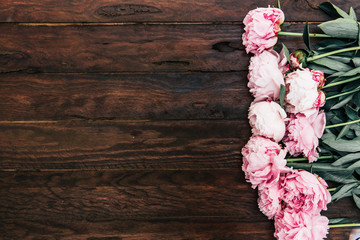 Wall Mural - pink peony flowers on wooden background. Minimal flat lay composition with copy space.