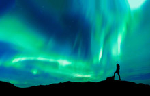 Aurora Borealis With Silhouette Standing Man On The Mountain.Freedom Traveller Journey Concept