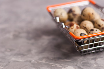 Poster - Full metal glossy market basket of spotted fresh quail eggs on old broken worn gray cement floor with copy space