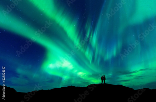 Fotomural Aurora borealis with silhouette love romantic couple on the mountain