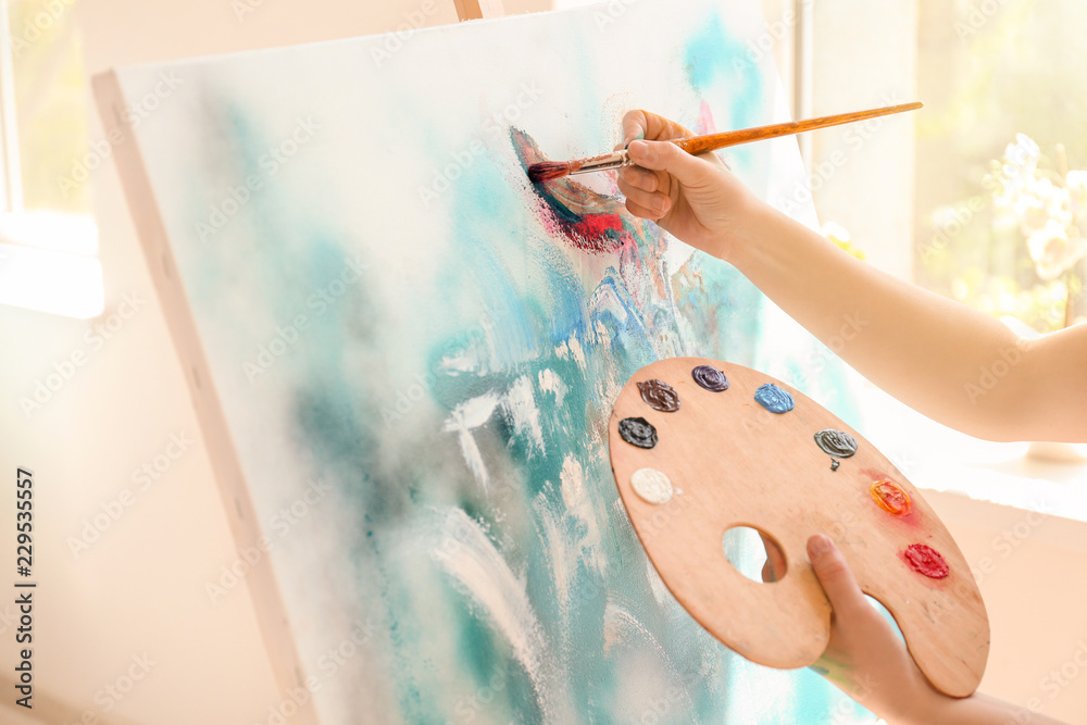 Female artist painting picture in workshop