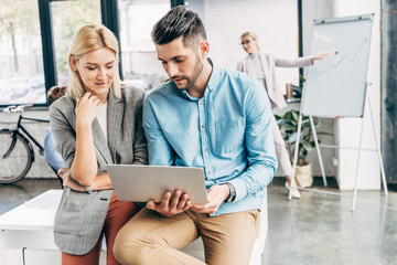 young businessman and businesswoman working with laptop in office