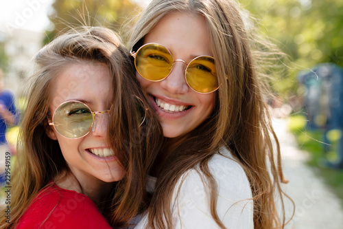Foto Close up outdoor portrait of two cheerful female best friends in bright glasses smilimg and posing at camera in sunny park