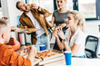 © LIGHTFIELD STUDIOS - group of young entrepreneurs eating pizza for lunch together while working on startup at office