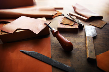 Leather craft or leather working. beautifully colored tanned leather on leather craftman's work desk with working tools.