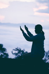 Wall Mural - Silhouette of teen girl kneeling and praying over beautiful sunrise background.