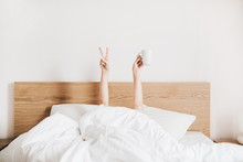 Hand's Of Young Woman With Coffee Mug In Bed With White Linens. Minimal Happy Morning Concept.
