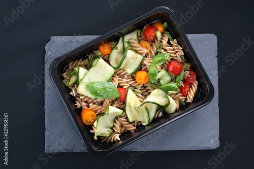 Fototapeta na szkło Catering dietetyczny. Sałatka makaronu z cukinią i pomidorami podana w naczyniu jednorazowym.