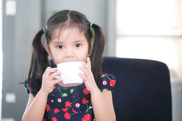 Asian child cute or kid girl delicious hot cocoa or chocolate and milkshake drink with holding white cup and funny or happy for breakfast in morning at home or cafe restaurant and coffee shop