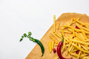 Wall Mural - top view of french fries with spicy peppers on parchment paper isolated on white