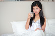 © feeling lucky - young beautiful woman holding a glass of water on bed