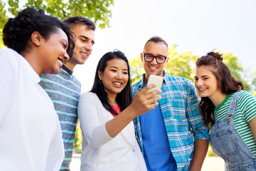 Wall Mural - friendship, technology and international concept - group of friends with smartphone at summer park