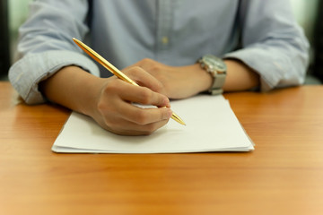 Wall Mural - Female hand with pen writing on document form on wooden table.