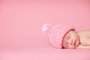 newborn baby girl in knit hat, isolated on pink, room for text