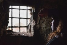 Young Woman Captive Or Prisoner Watching Desperately Out From The Window Of Her Underground Cell